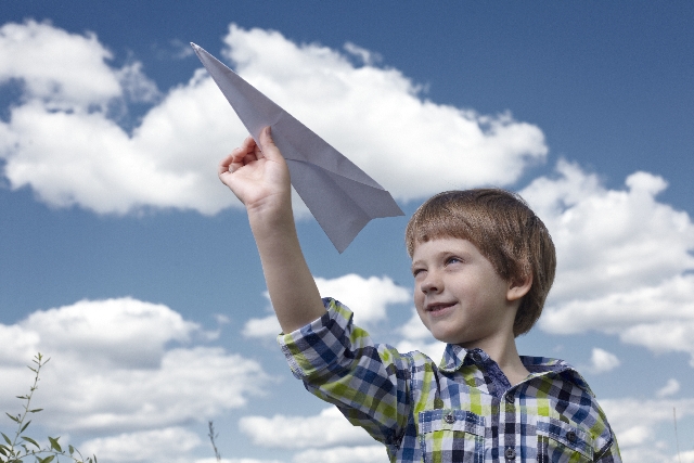 紙飛行機を飛ばす子供